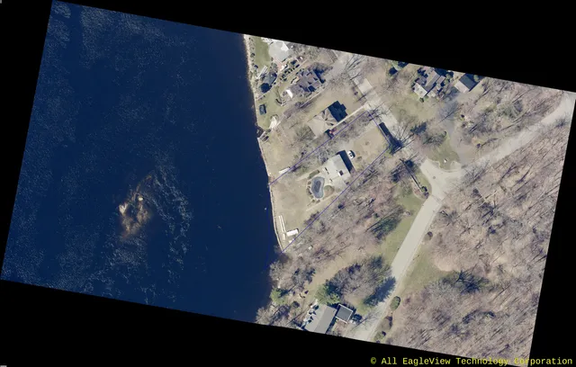 Oblique aerial orthophoto of the shoreline property at 501 Main St, showing the outlined parcel, existing house and driveway, adjacent homes, and the large body of water to the west.