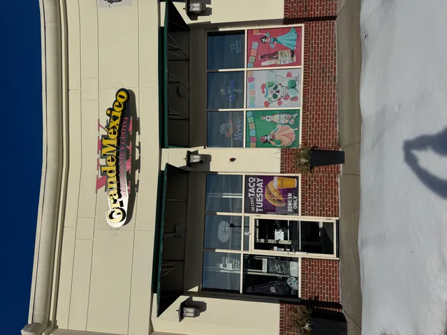 Street-level photo of a restaurant storefront showing the existing "Grande Méxio" wall sign mounted above the entrance, with windows, awnings, and the facade below it.