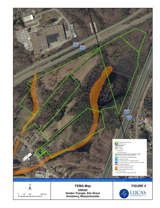 A FEMA flood hazard map overlaid on aerial imagery of the Elm Street/Route I-95 area in Amesbury, showing approximate parcel boundaries, town/city boundary lines, roads, and shaded flood zones around the Golden Triangle site.