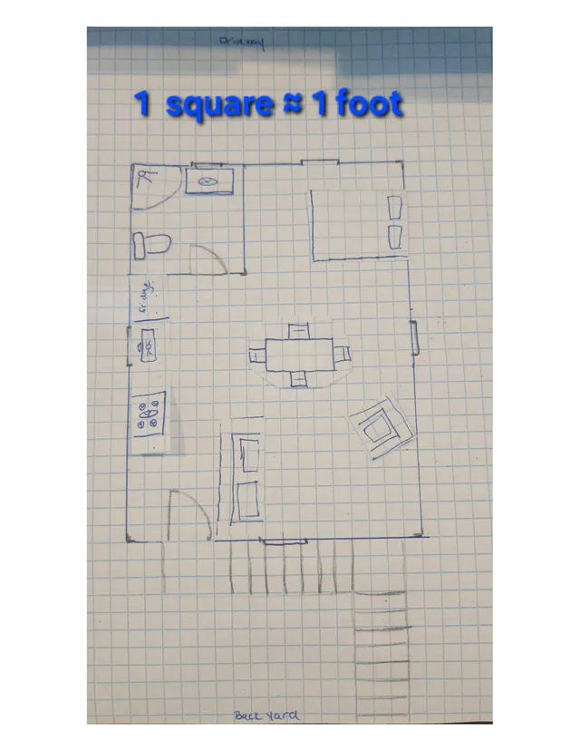 Hand-drawn floor plan sketch on graph paper showing a small building layout with rooms, doors, fixtures, stairs, and notes such as "1 square ≈ 1 foot," "Driveway," and "Back Yard."