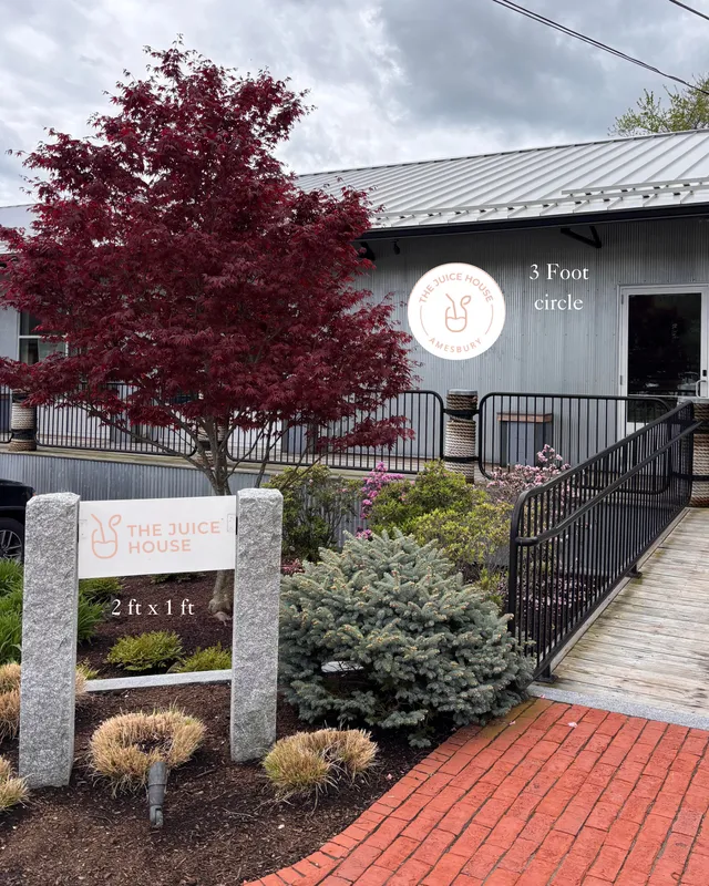 Photo of the building exterior with a sign mockup overlay for The Juice House in Amesbury, showing proposed sign locations and sizes on the corrugated metal facade and monument sign.