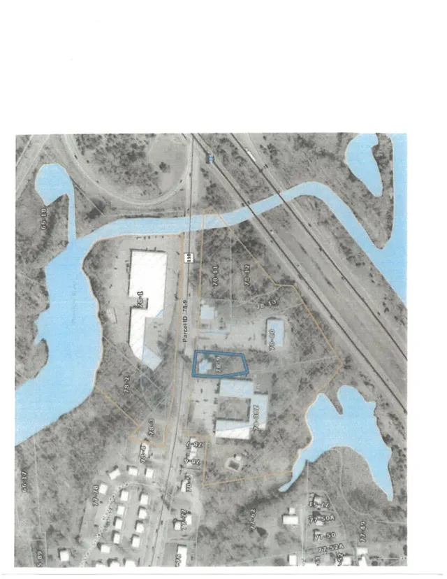 Oblique aerial/satellite-style map showing the parcel and surrounding area near railroad tracks, roads, and water bodies, with property boundaries and tax parcel labels overlaid.